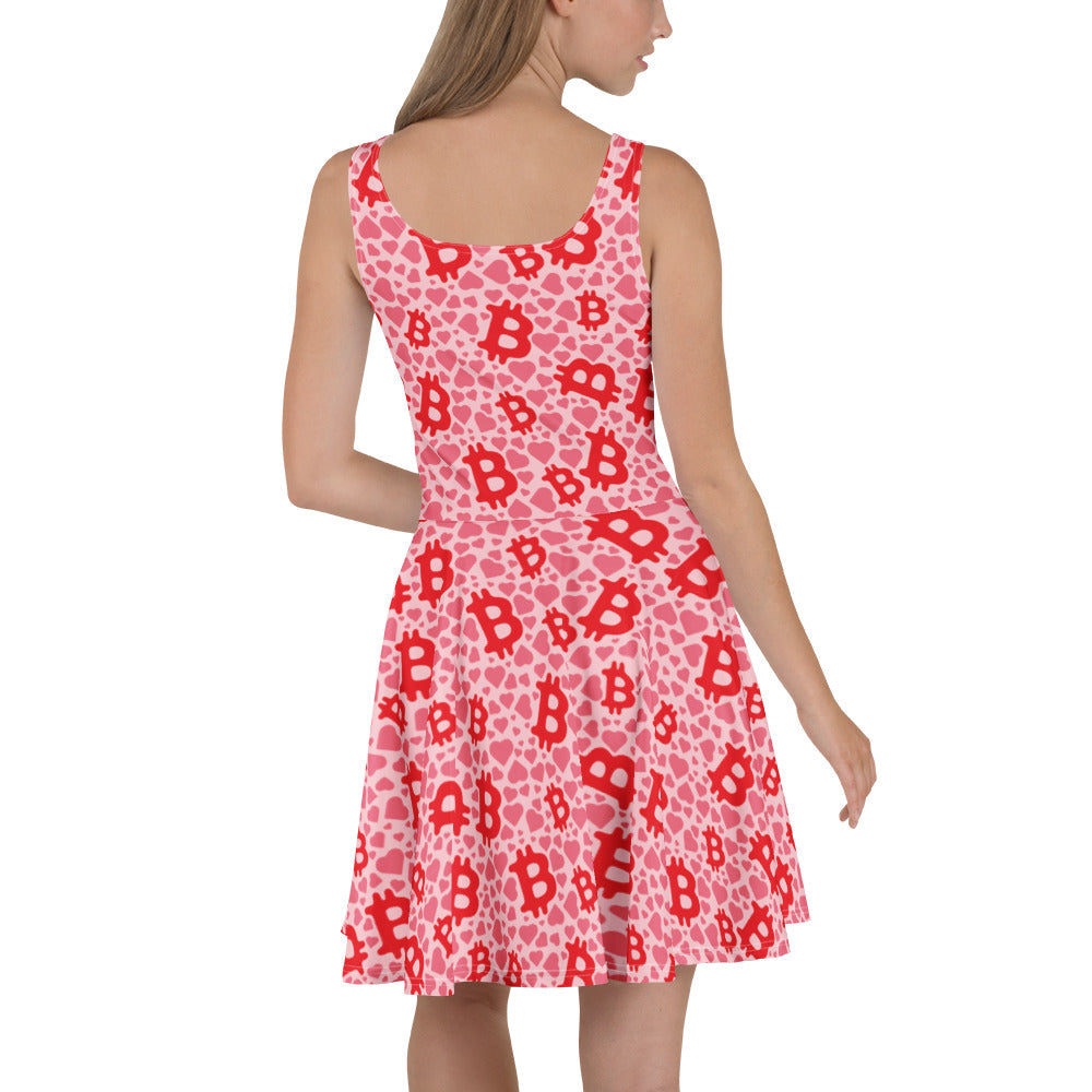 Woman wearing a pink dress with red hearts and bitcoin logos pattern on a white background