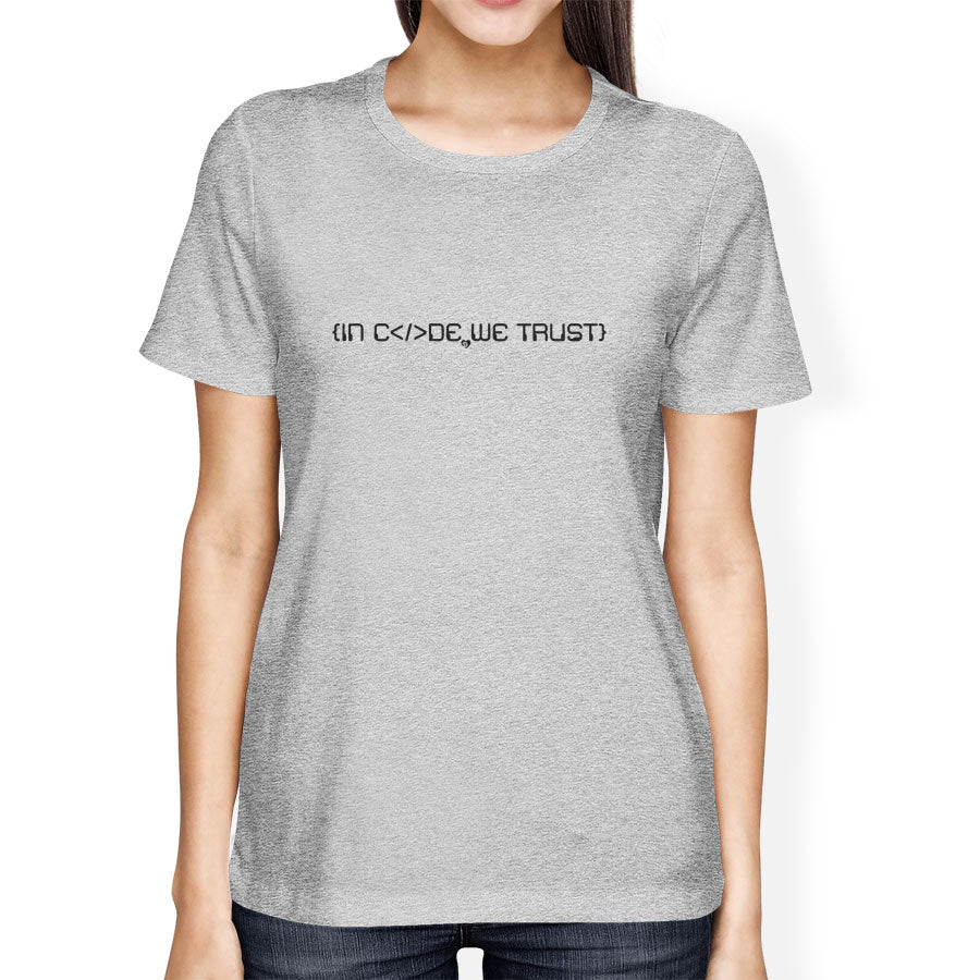 Person wearing a gray t-shirt with in code we trust text on a white background