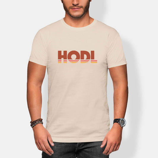 Man wearing a beige t-shirt with 'HODL' printed on it against a plain background