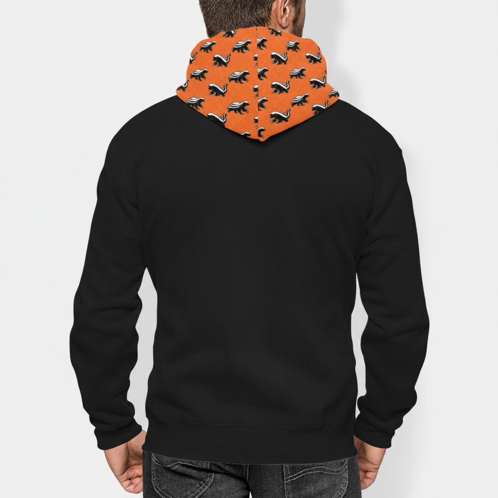 Person wearing a black hoodie with an orange honey badger don't care pattern on the hood against a white background