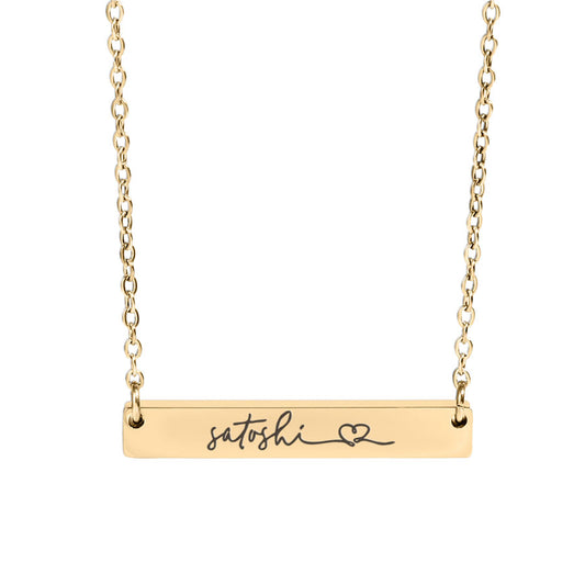 Gold necklace with a bar pendant engraved with 'satoshi' and a heart symbol on a white background