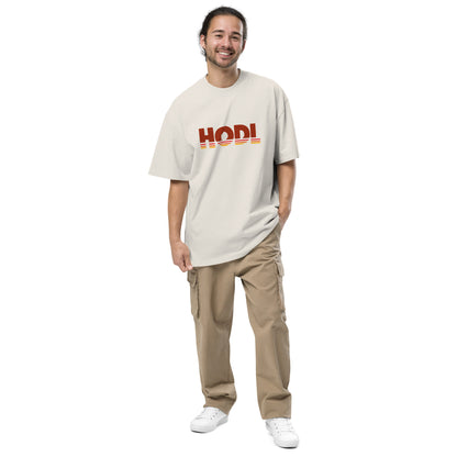 Man wearing a beige t-shirt with 'HODL' logo and beige pants on a white background