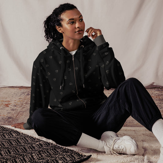 Person wearing a black hoodie with grey bitcoin hearts and pants sitting on a textured rug.