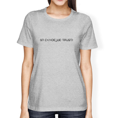 Person wearing a gray t-shirt with in code we trust text on a white background