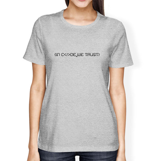Person wearing a gray t-shirt with in code we trust text on a white background